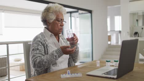 African-american-senior-woman-medicine-in-front-of-laptop-at-home