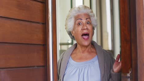 Porträt-Einer-Afroamerikanischen-Seniorin,-Die-Die-Haustür-öffnet-Und-Zu-Hause-Willkommen-Heißt