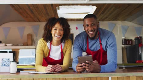 Portrait-of-african-american-couple-wearing-aprons-smiling-in-food-truck