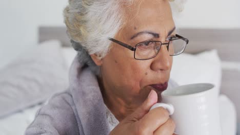 Nahaufnahme-Einer-Afroamerikanischen-Seniorin,-Die-Kaffee-Trinkt,-Während-Sie-Zu-Hause-Auf-Dem-Bett-Sitzt