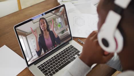 African-american-male-college-student-holding-notes-while-having-a-video-call-on-laptop-at-home