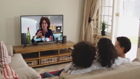Rear-view-of-african-amerrican-family-having-a-video-call-on-tv-while-sitting-on-the-couch-at-home