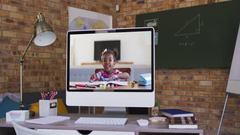 Webcam-view-of-african-american-girl-on-video-call-on-computer-on-table-at-school