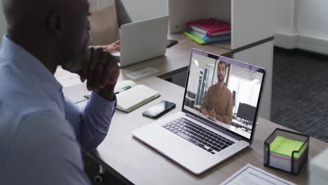 Afroamerikanischer-Mann,-Der-Im-Büro-Einen-Videoanruf-Mit-Einer-Kollegin-Auf-Einem-Laptop-Führt