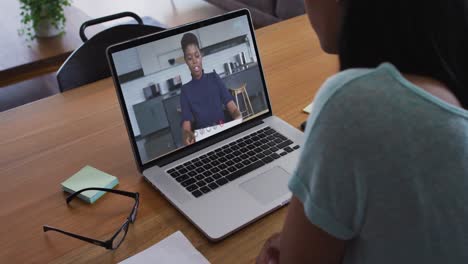 Mid-section-of-african-american-woman-having-a-video-call-with-female-colleague-on-laptop