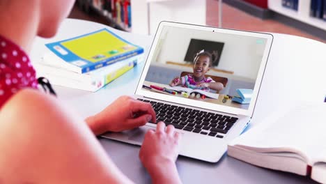 Mid-section-of-caucasian-female-teacher-having-a-video-call-with-school-girl-on-laptop-at-school