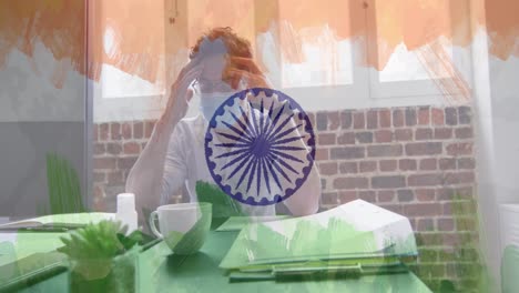 Composition-of-tired-businessman-wearing-face-mask-in-office-over-indian-flag