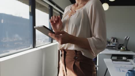Midsection-of-caucasian-businesswoman-standing-and-using-tablet