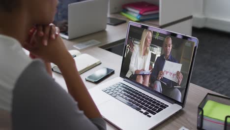 African-american-woman-having-a-video-call-with-male-and-female-colleagues-on-laptop-at-office