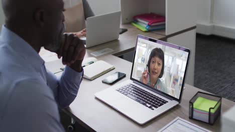 African-american-businessman-sitting-at-desk-using-laptop-having-video-call-with-female-colleague