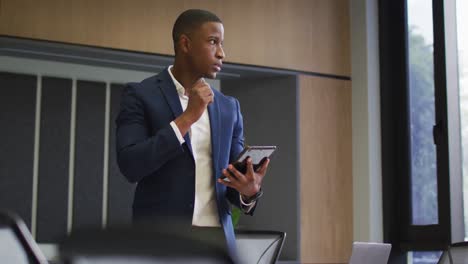 African-american-businessman-using-tablet-in-conference-room-in-modern-office