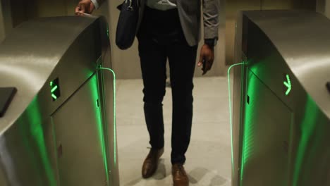 Midsection-of-african-american-businessman-arriving-in-modern-office-using-pass-at-security-gates