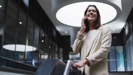 Smiling-caucasian-businesswoman-using-smartphone-in-lobby-of-modern-office