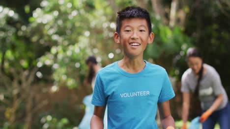 Laughing-asian-boy-wearing-volunteer-t-shirt-holding-refuse-sack-for-collecting-plastic-waste