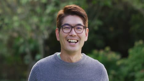 Portrait-of-happy-asian-man-looking-to-camera-smiling-and-laughing-in-garden