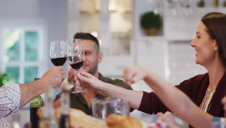 Smiling-caucasian-mother-making-a-toast-with-husband-and-father-at-table-before-family-meal