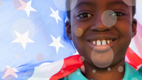 Animation-of-white-circles-moving-over-african-american-boy-holding-american-flag