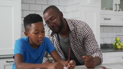 Afroamerikanischer-Vater-Sitzt-Am-Küchentisch-Und-Hilft-Seinem-Sohn-Bei-Der-Schularbeit