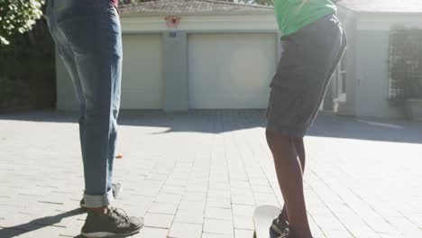 African-american-dad-teaching-his-son-to-skateboard-in-the-front-yard