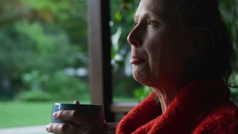 Nachdenkliche-ältere-Kaukasische-Frau,-Die-Kaffee-Trinkt-Und-Aus-Dem-Fenster-Schaut