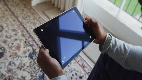 Mittelteil-Eines-Afroamerikanischen-Mannes,-Der-Zu-Hause-Ein-Digitales-Tablet-Mit-Kopierplatz-Hält