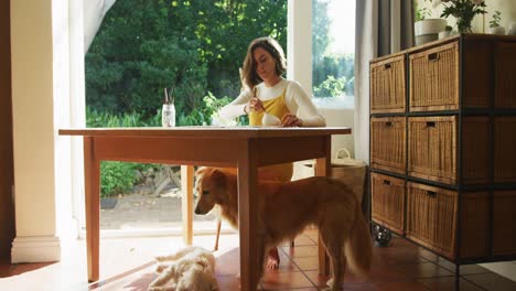 Caucasian-woman-painting-at-home-with-her-pet-dog-next-to-her