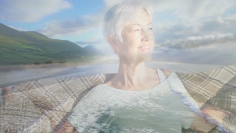 Animation-of-glowing-light-over-smiling-senior-woman-by-seaside