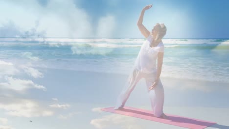 Animation-of-glowing-light-over-senior-woman-practicing-yoga-by-seaside