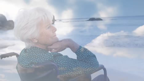 Animation-of-glowing-light-over-senior-woman-in-wheelchair-by-seaside