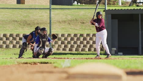 Diverse-group-of-female-baseball-players-playing-on-the-field,-hitter-swinging-for-pitched-ball
