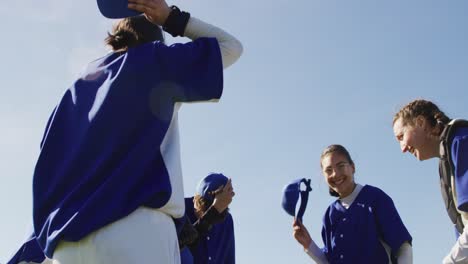 Happy-diverse-team-of-female-baseball-players-throwing-caps-in-the-air,celebrating-after-game