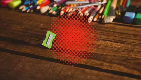 Animation-of-pencil-sharpener-and-eraser-bouncing-on-red-dots-over-desk-with-pencils