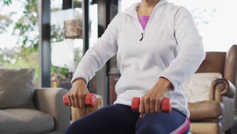 Senior-mixed-race-woman-excercising,-lifting-dumbbells