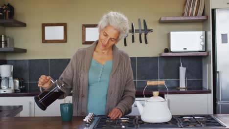 Portrait-of-senior-mixed-race-woman-preparing-coffee-in-kitchen