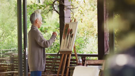 Senior-mixed-race-woman-painting-on-balcony