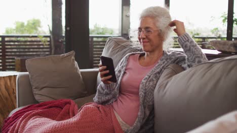 Mujer-De-Raza-Mixta-Senior-Sentada-En-Un-Sofá-Usando-Un-Teléfono-Inteligente