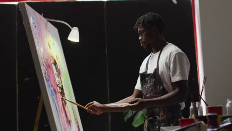 Artista-Masculino-Afroamericano-Con-Delantal-Pintando-Sobre-Lienzo-En-El-Estudio-De-Arte