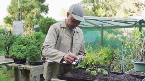 Mixed-race-male-gardener-making-notes-at-garden-center