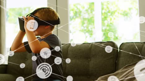 Animation-of-network-of-connections-with-icons-over-boy-wearing-vr-headset