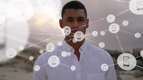 Network-of-digital-icons-against-portrait-of-man-standing-at-the-beach