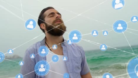 Animation-of-network-of-connections-with-people-icons-over-man-relaxing-by-sea