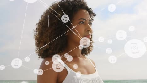 Animation-of-network-of-connections-with-icons-over-woman-in-beach