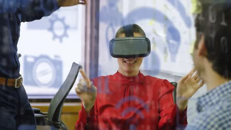 Mehrere-Blaue-Digitale-Symbole-Schweben-Vor-Einer-Kaukasischen-Geschäftsfrau,-Die-Im-Büro-Ein-VR-Headset-Trägt