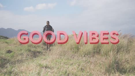 Animation-of-the-words-good-vibes-in-pink-over-woman-hiking-in-countryside