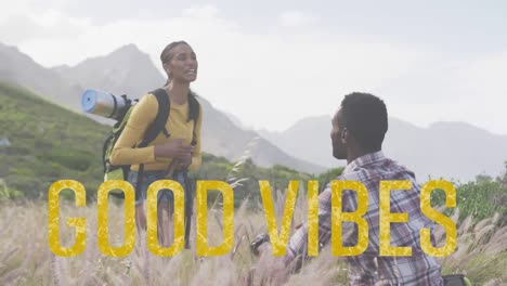 Animation-of-the-words-good-vibes-in-yellow-over-happy-couple-hiking-in-mountains