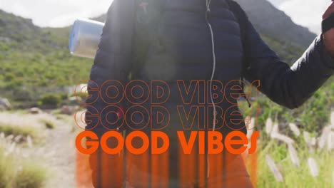 Animation-of-the-words-good-vibes-written-in-orange-over-person-hiking-in-mountains
