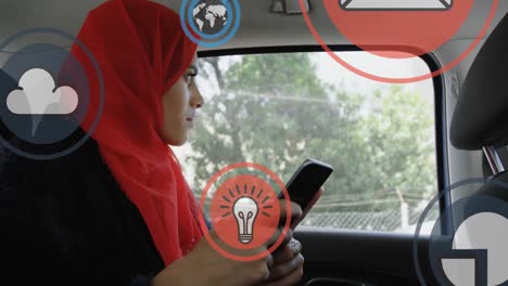 Mehrere-Digitale-Symbole-Schweben-Einer-Frau-Im-Hijab-Entgegen,-Die-Ihr-Smartphone-Im-Auto-Benutzt