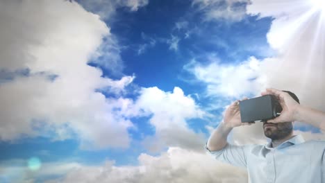 Kaukasischer-Mann-Mit-VR-Headset-Vor-Lichtfleck-Und-Wolken-Am-Himmel