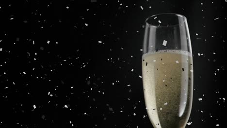 Animation-of-glass-of-champagne,-with-confetti-falling-on-black-background