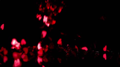 Animation-of-red-kaleidoscope-shapes-and-red-hearts-falling-on-black-background